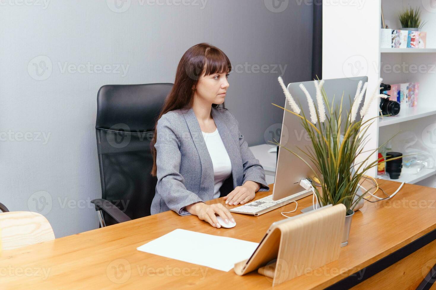 A brunette woman at a computer in the workplace. Business concept. photo