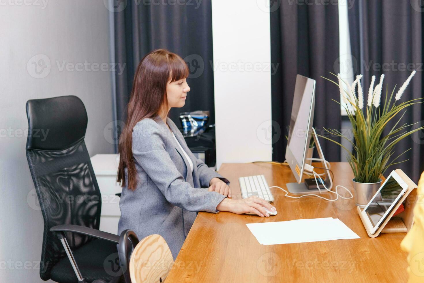 A brunette woman at a computer in the workplace. Business concept. photo