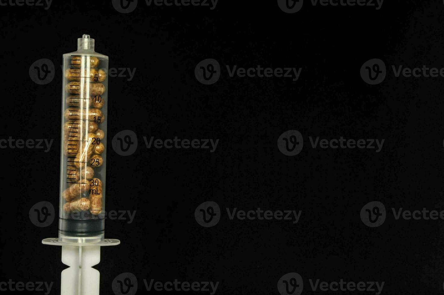 A syringe with pills on black background photo