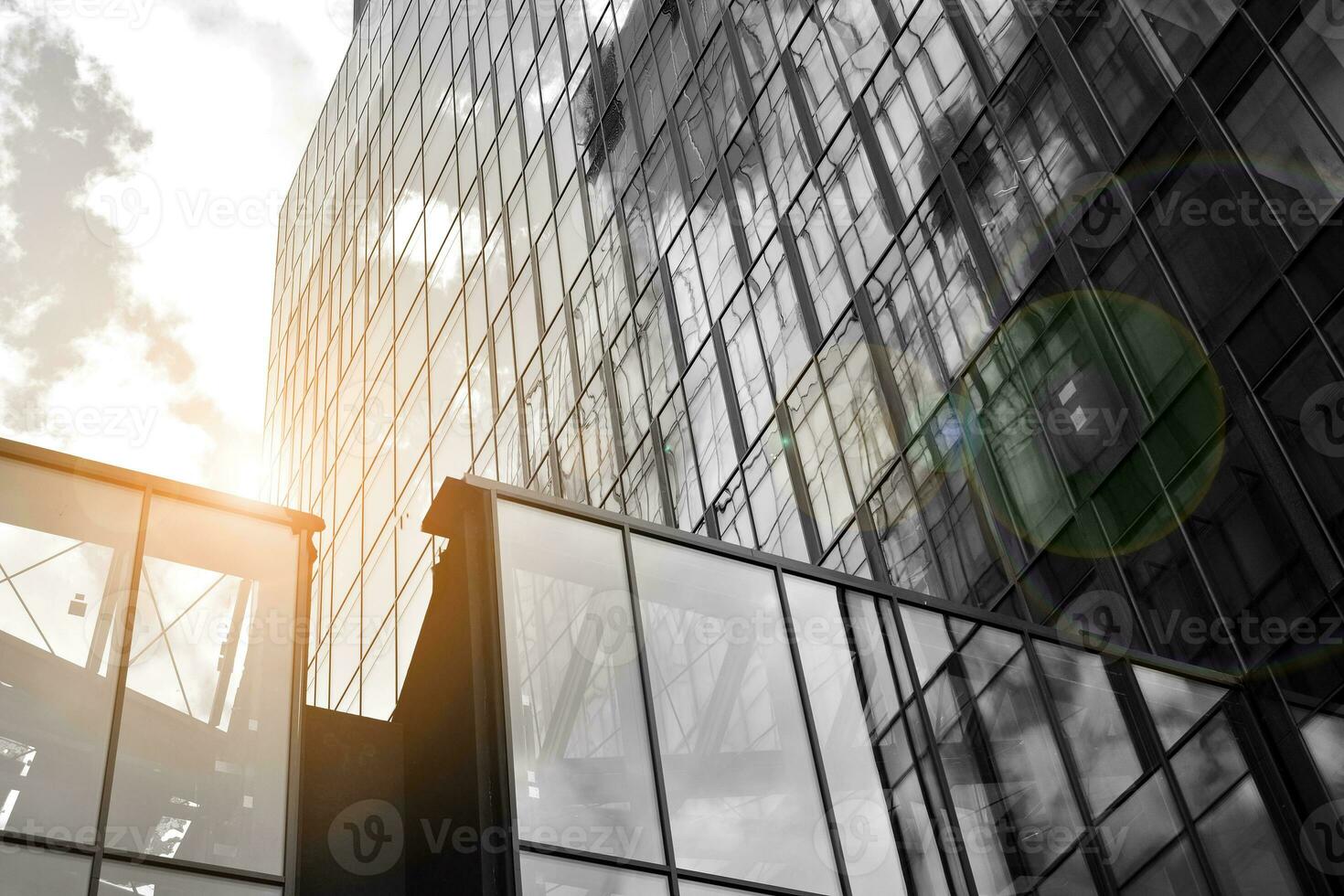 Modern architectural details. Modern glass facade with a geometric pattern. Contemporary corporate business architecture. Red sun on horizon. Black and white toned image. photo