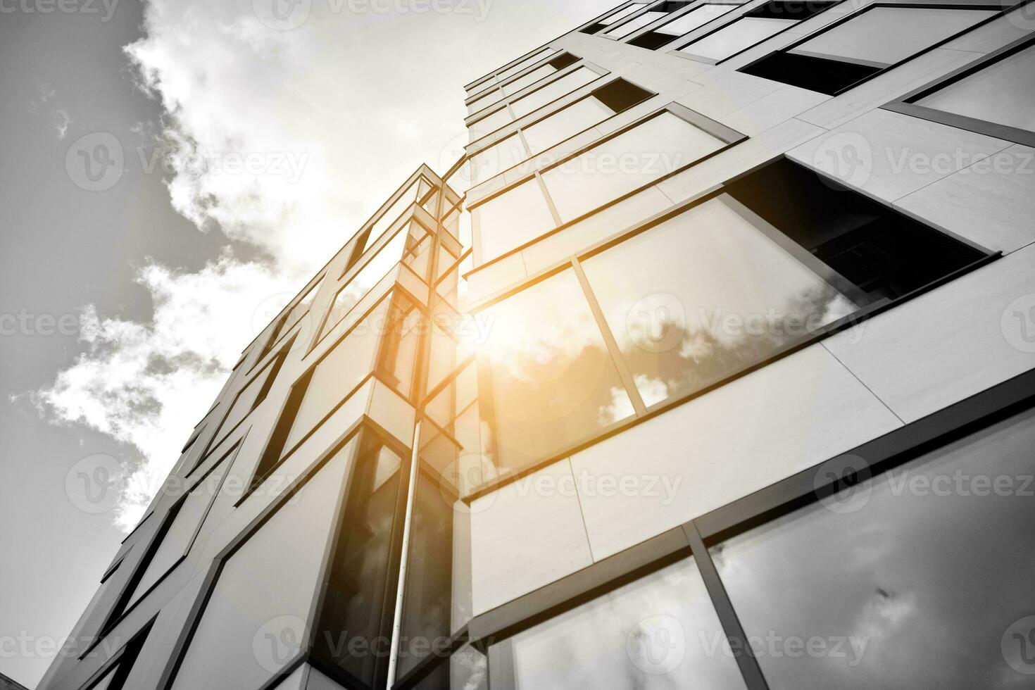 Modern architectural details. Modern glass facade with a geometric pattern. Contemporary corporate business architecture. Red sun on horizon. Black and white toned image. photo