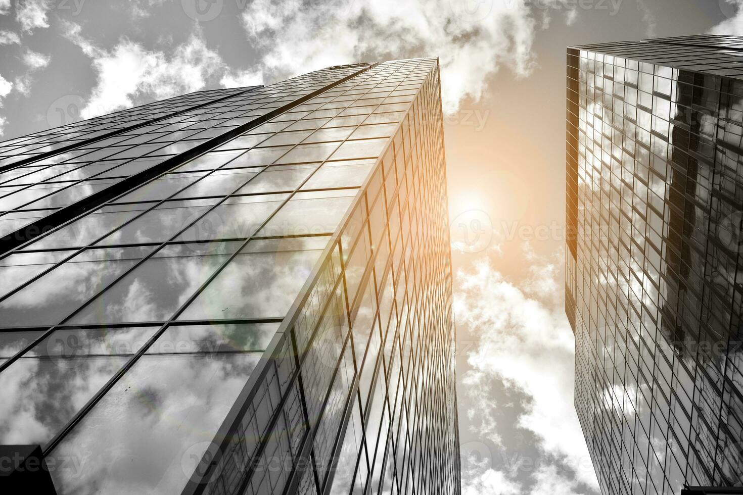 Modern architectural details. Modern glass facade with a geometric pattern. Contemporary corporate business architecture. Red sun on horizon. Black and white toned image. photo