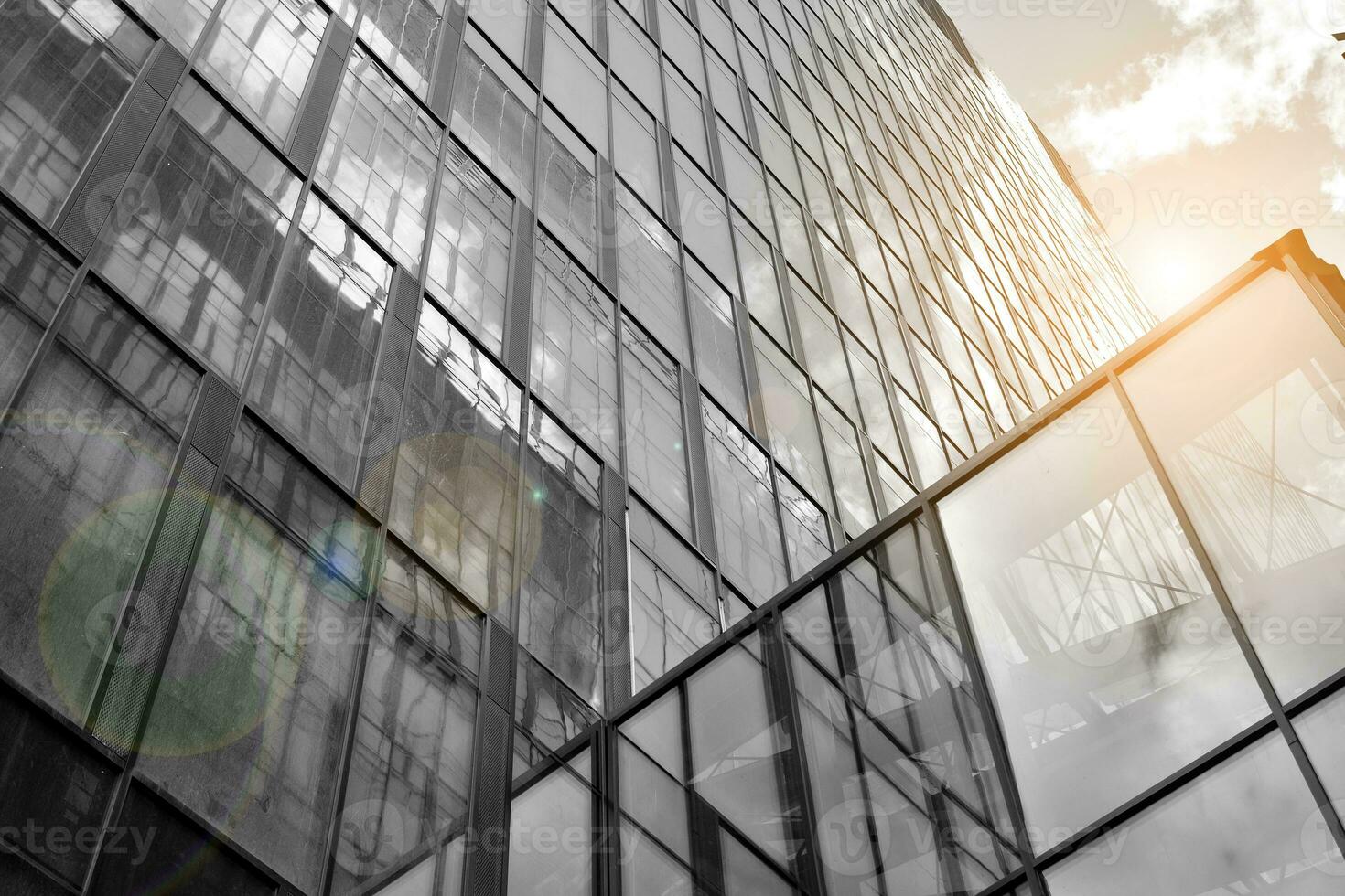 Modern architectural details. Modern glass facade with a geometric pattern. Contemporary corporate business architecture. Red sun on horizon. Black and white toned image. photo