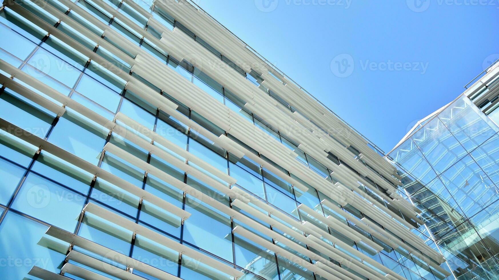 Glass building with transparent facade of the building and blue sky. Structural glass wall reflecting blue sky. Abstract modern architecture fragment. Contemporary architectural background. photo