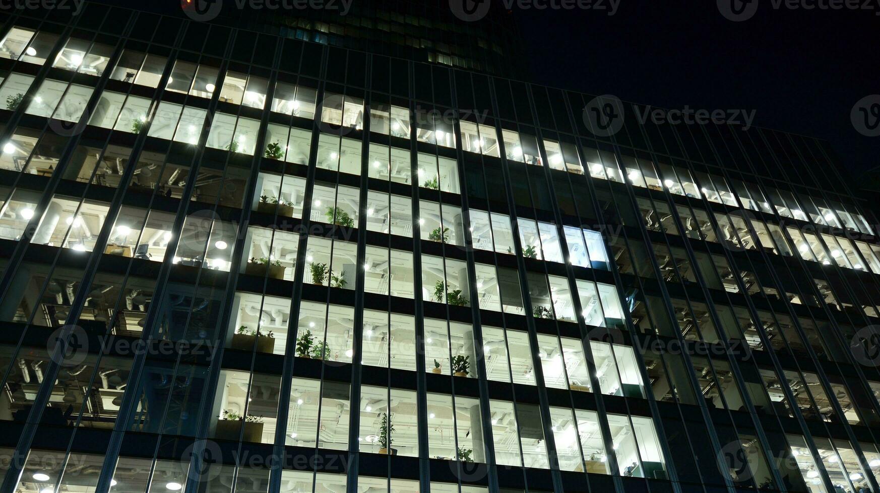 Pattern of office buildings windows illuminated at night. Glass architecture ,corporate building at night - business concept. photo