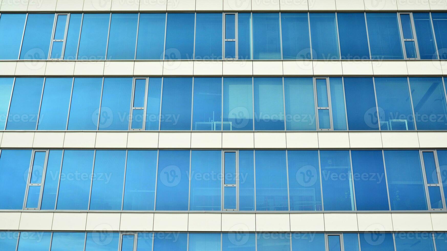 Glass building with transparent facade of the building and blue sky. Structural glass wall reflecting blue sky. Abstract modern architecture fragment. Contemporary architectural background. photo