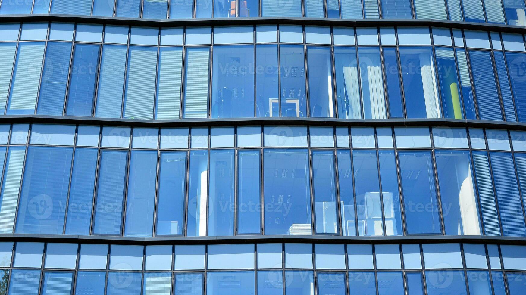 Glass building with transparent facade of the building and blue sky. Structural glass wall reflecting blue sky. Abstract modern architecture fragment. Contemporary architectural background. photo