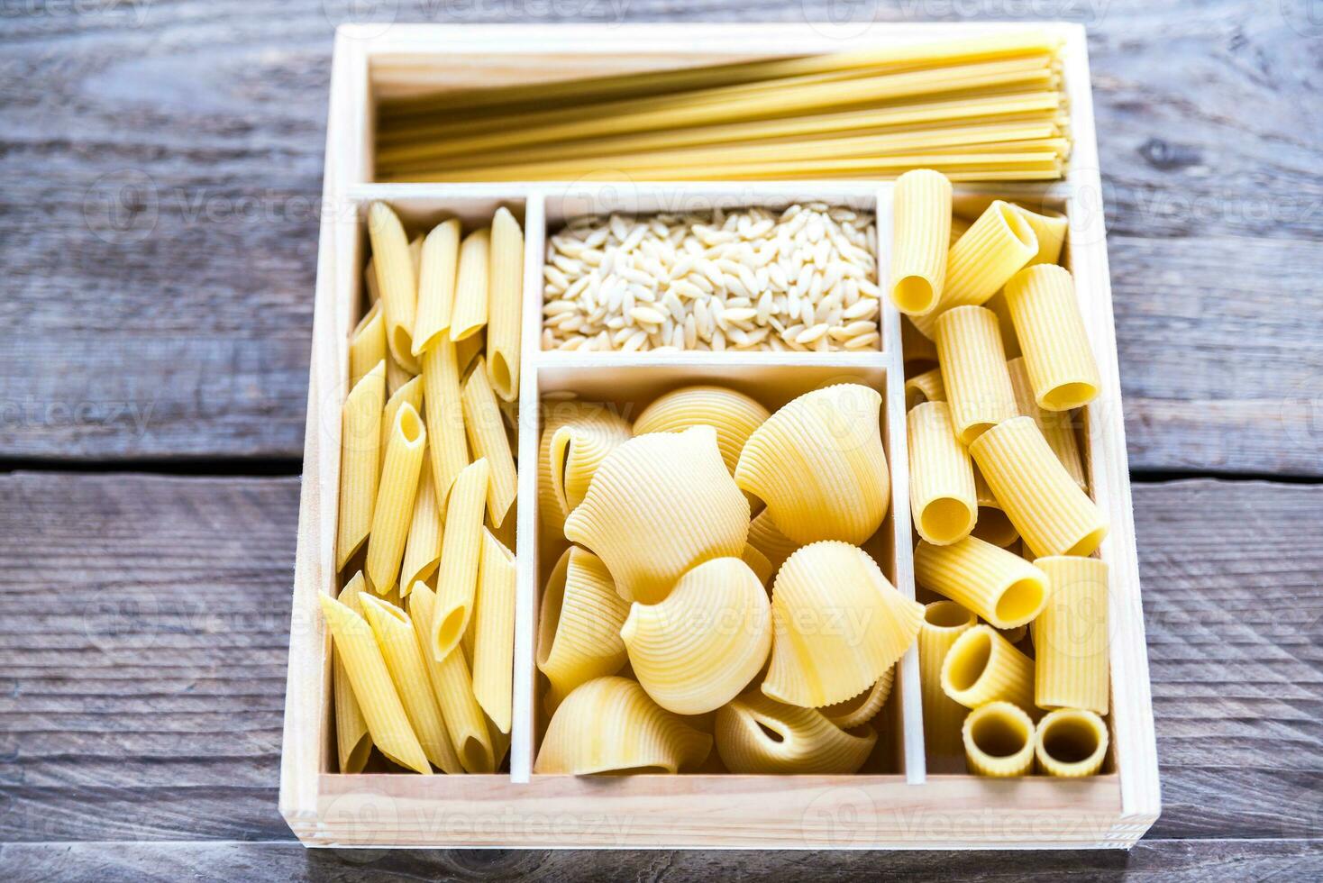 Various types of pasta in the wooden container photo