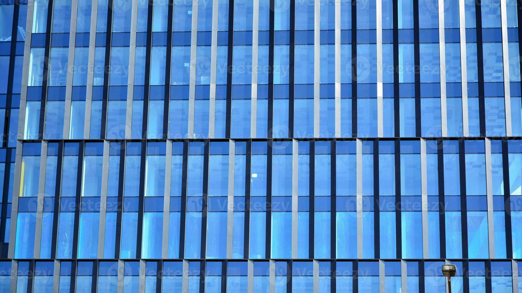 Glass building with transparent facade of the building and blue sky. Structural glass wall reflecting blue sky. Abstract modern architecture fragment. Contemporary architectural background. photo