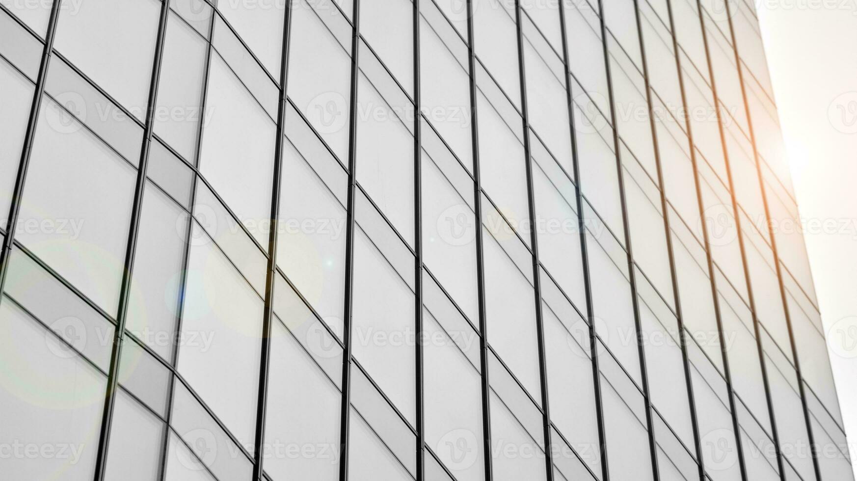 Glass modern building with blue sky background. View and architecture details. Urban abstract - windows of glass office building in  sunlight day. Black and white. photo