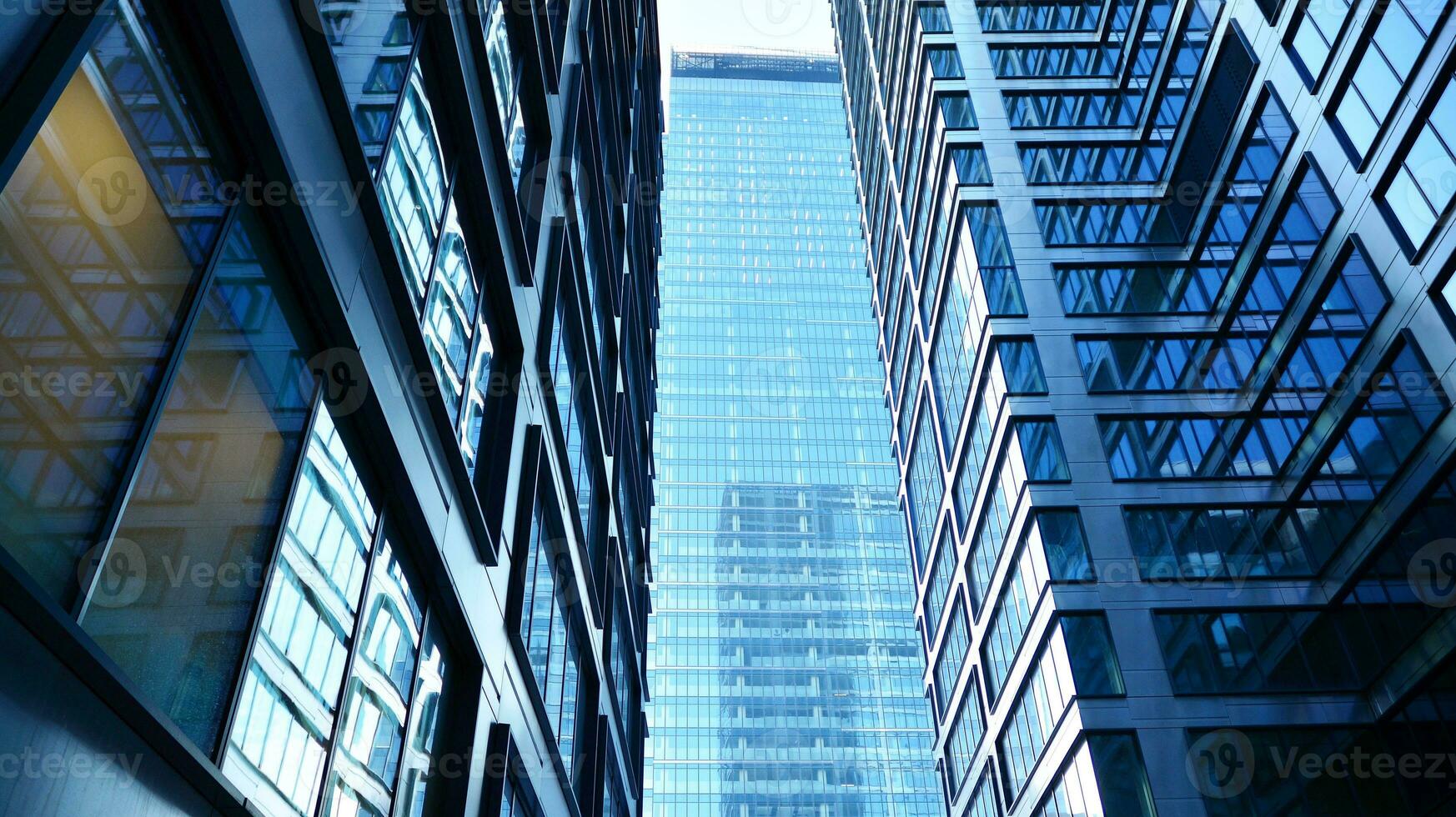Bottom view of modern skyscrapers in business district against blue sky. Looking up at business buildings in downtown. photo