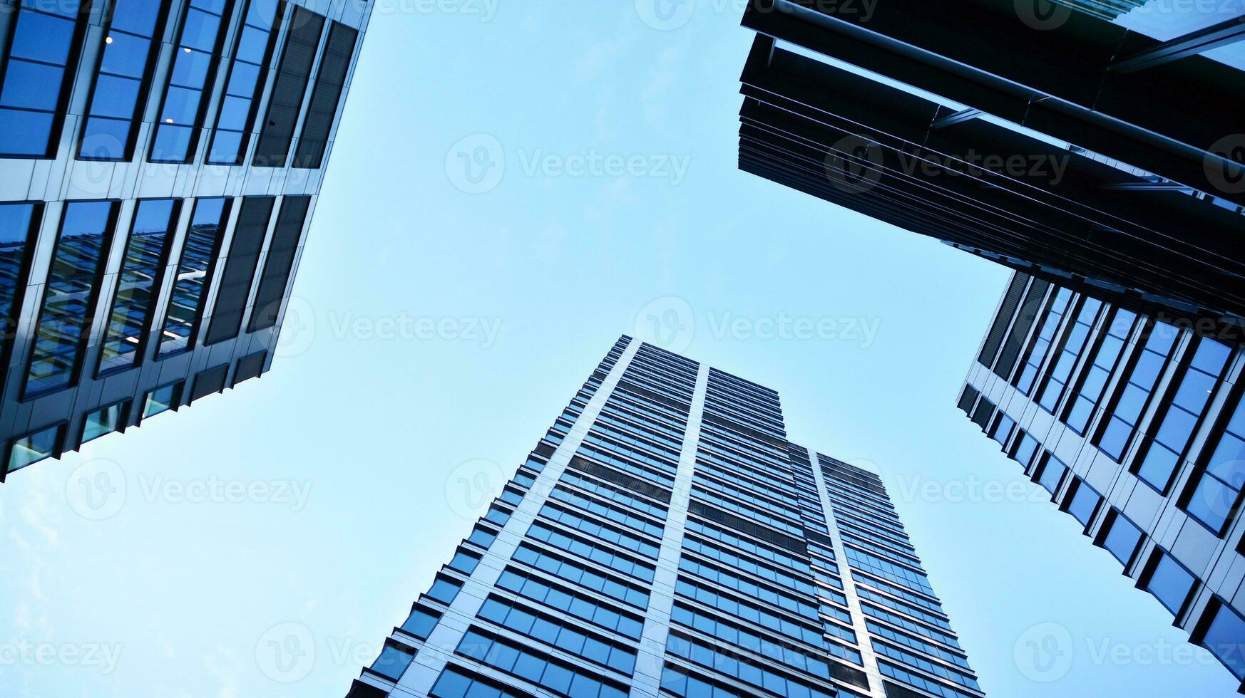 Bottom view of modern skyscrapers in business district against blue sky. Looking up at business buildings in downtown. photo