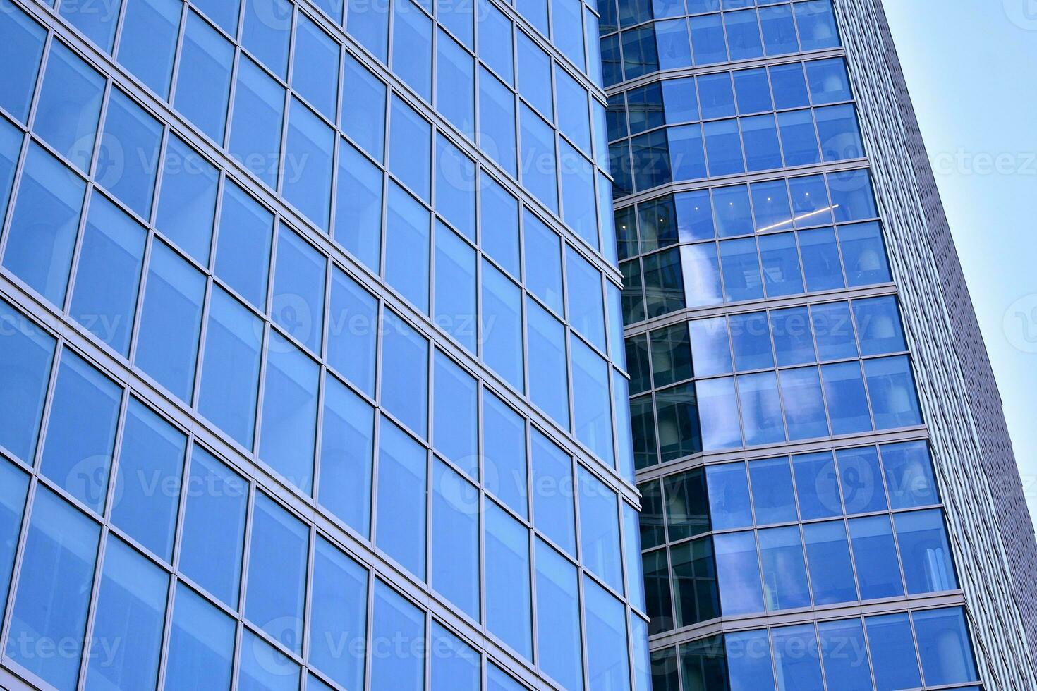 Modern office building with glass facade on a clear sky background. Transparent glass wall of office building. photo