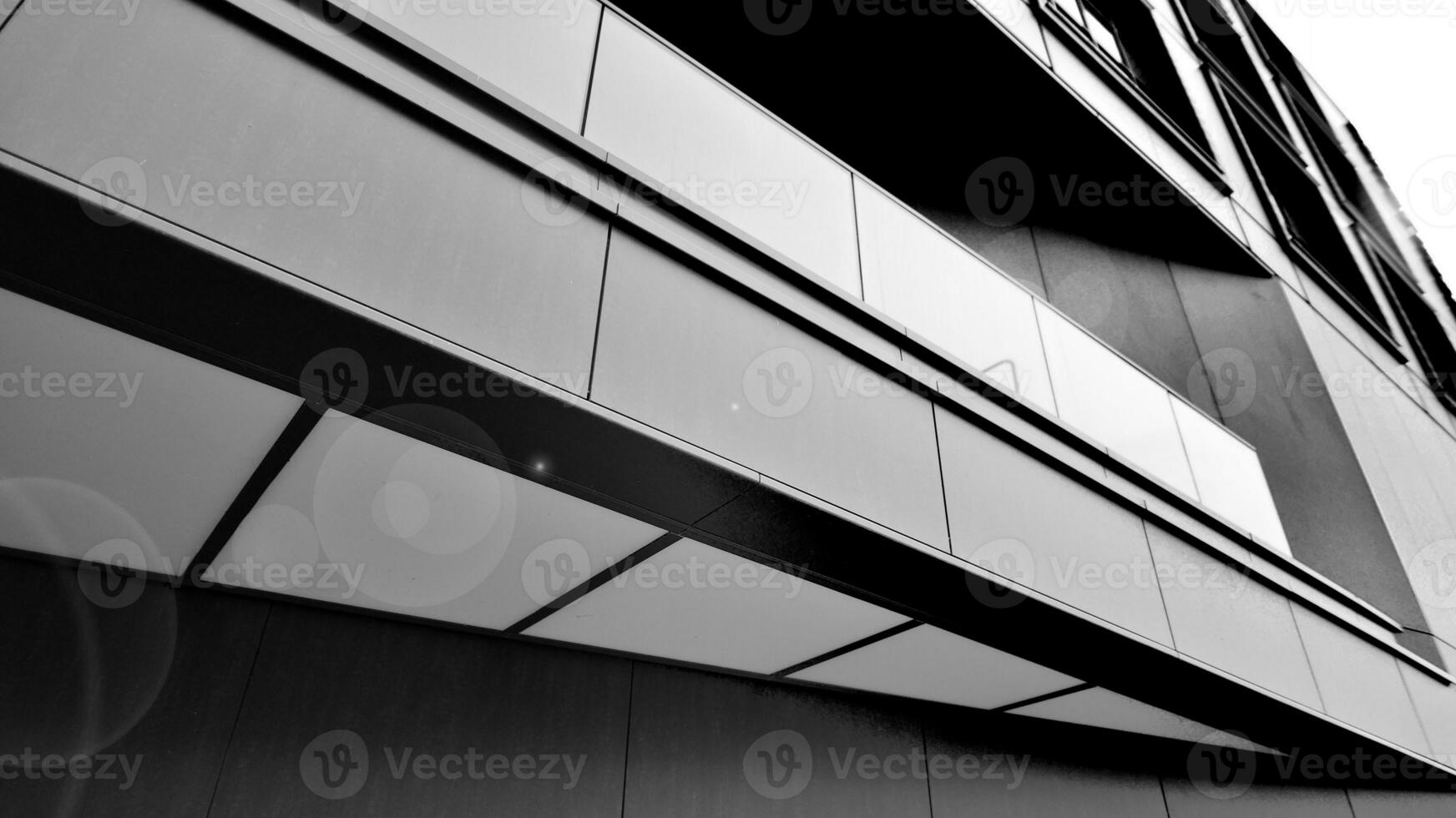 A view at a straight facade of a modern building with a dark grey facade. Dark grey metallic panel facad. Modern architectural details. Black and white. photo