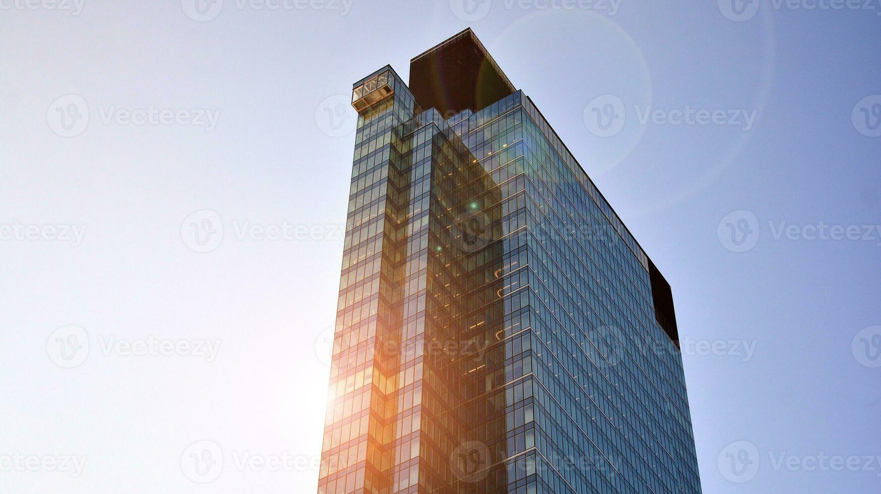 Modern office building with glass facade on a clear sky background. Transparent glass wall of office building. photo