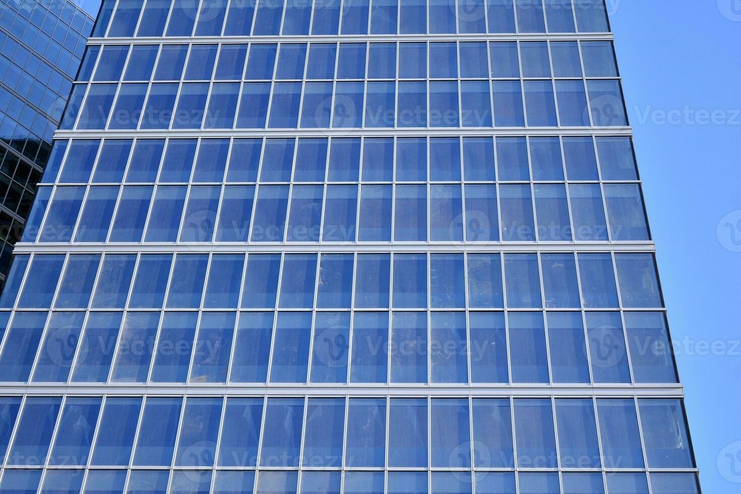 Glass building with transparent facade of the building and blue sky. Structural glass wall reflecting blue sky. Abstract modern architecture fragment. Contemporary architectural background. photo