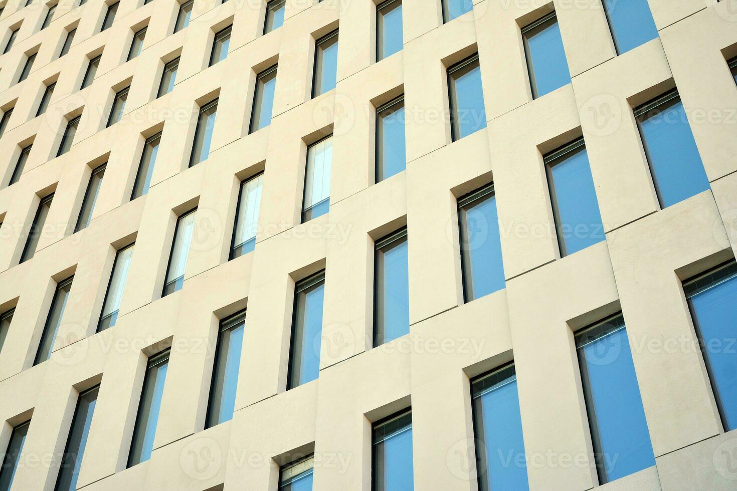 Modern office building detail. Perspective view of geometric angular concrete windows on the facade of a modernist brutalist style building. photo
