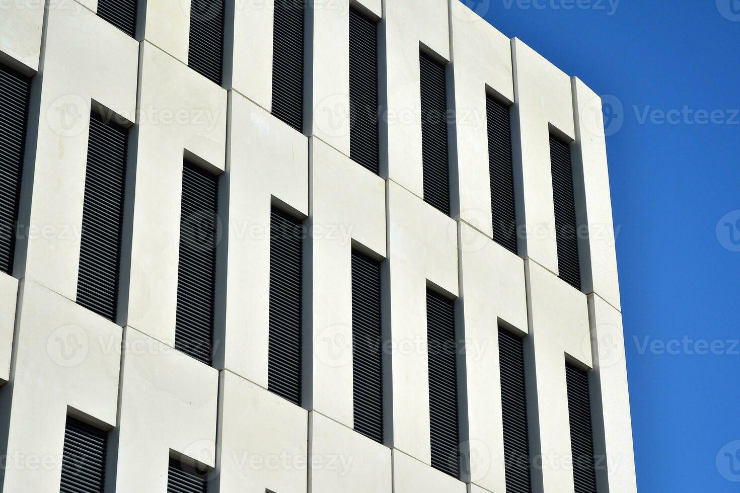 Modern office building detail. Perspective view of geometric angular concrete windows on the facade of a modernist brutalist style building. photo