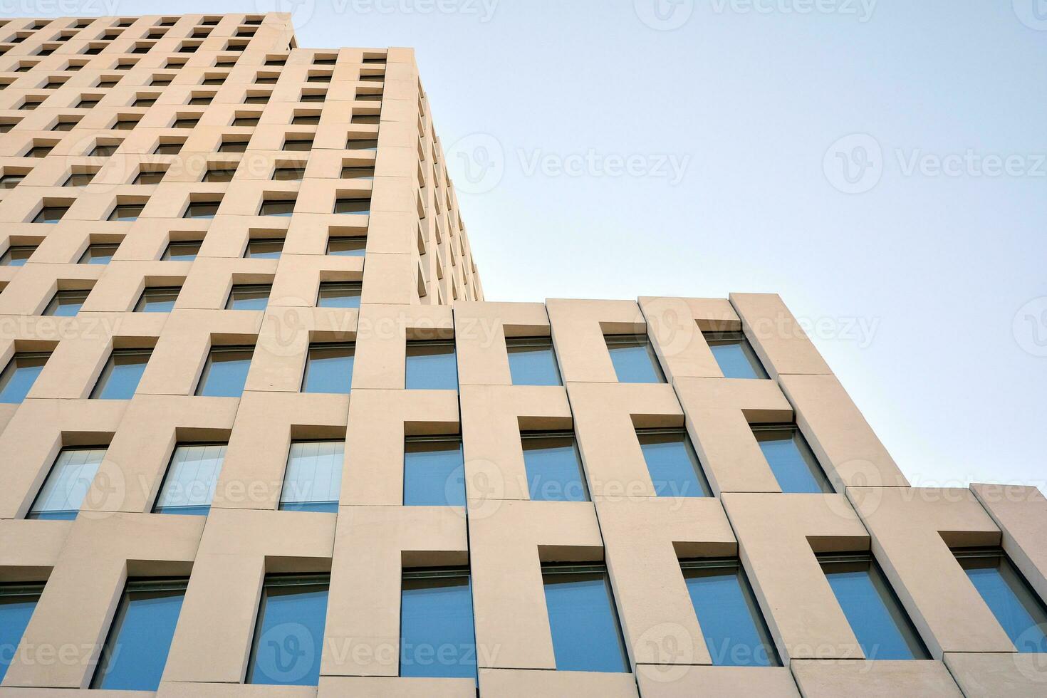 Modern office building detail. Perspective view of geometric angular concrete windows on the facade of a modernist brutalist style building. photo