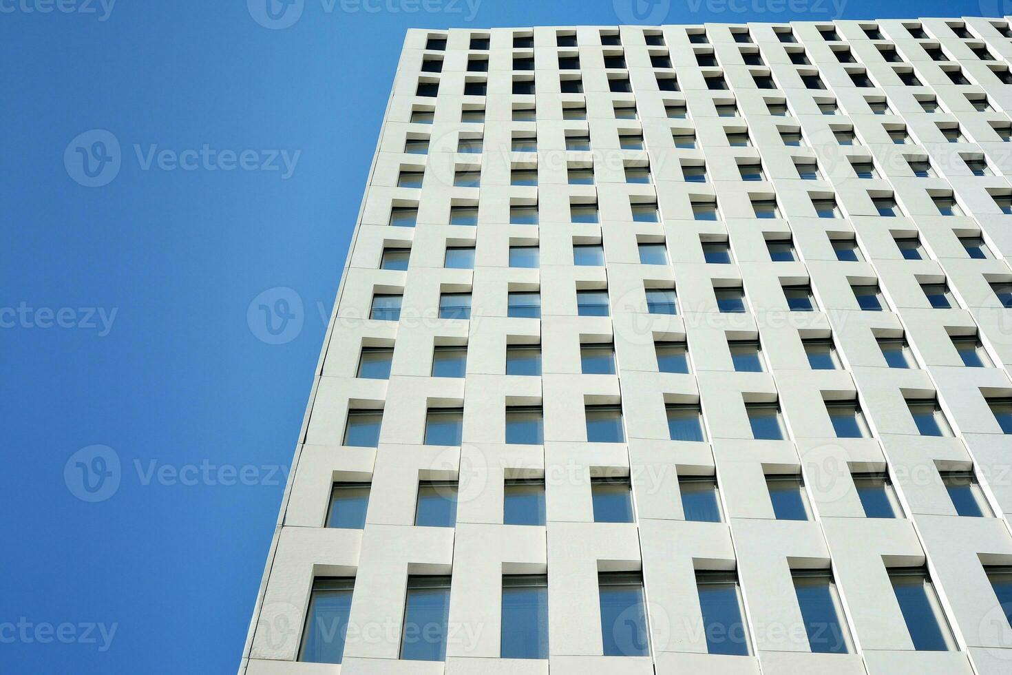 Modern office building detail. Perspective view of geometric angular concrete windows on the facade of a modernist brutalist style building. photo