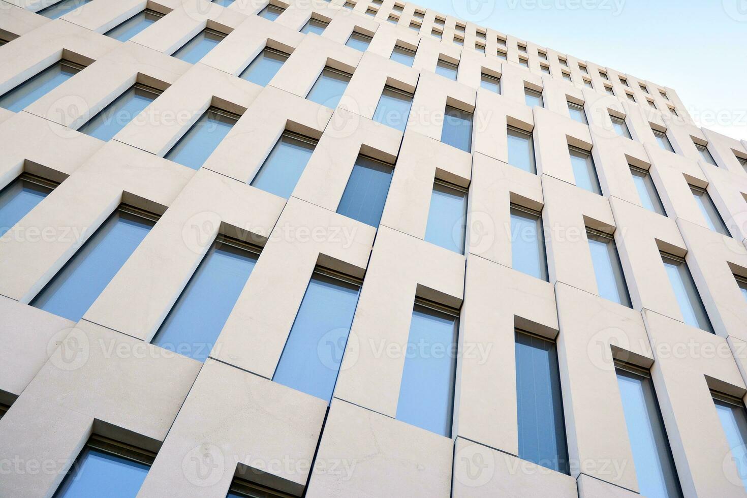 Modern office building detail. Perspective view of geometric angular concrete windows on the facade of a modernist brutalist style building. photo