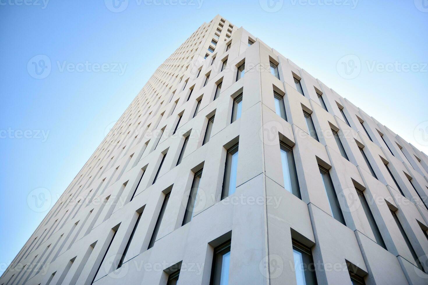 Modern office building detail. Perspective view of geometric angular concrete windows on the facade of a modernist brutalist style building. photo