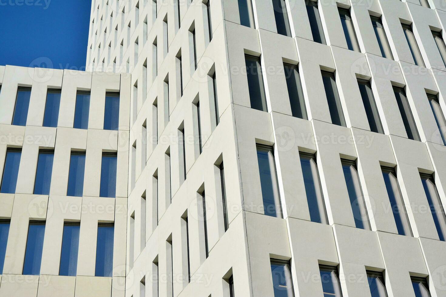 Modern office building detail. Perspective view of geometric angular concrete windows on the facade of a modernist brutalist style building. photo
