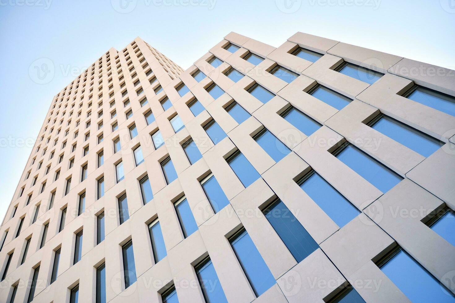 Modern office building detail. Perspective view of geometric angular concrete windows on the facade of a modernist brutalist style building. photo
