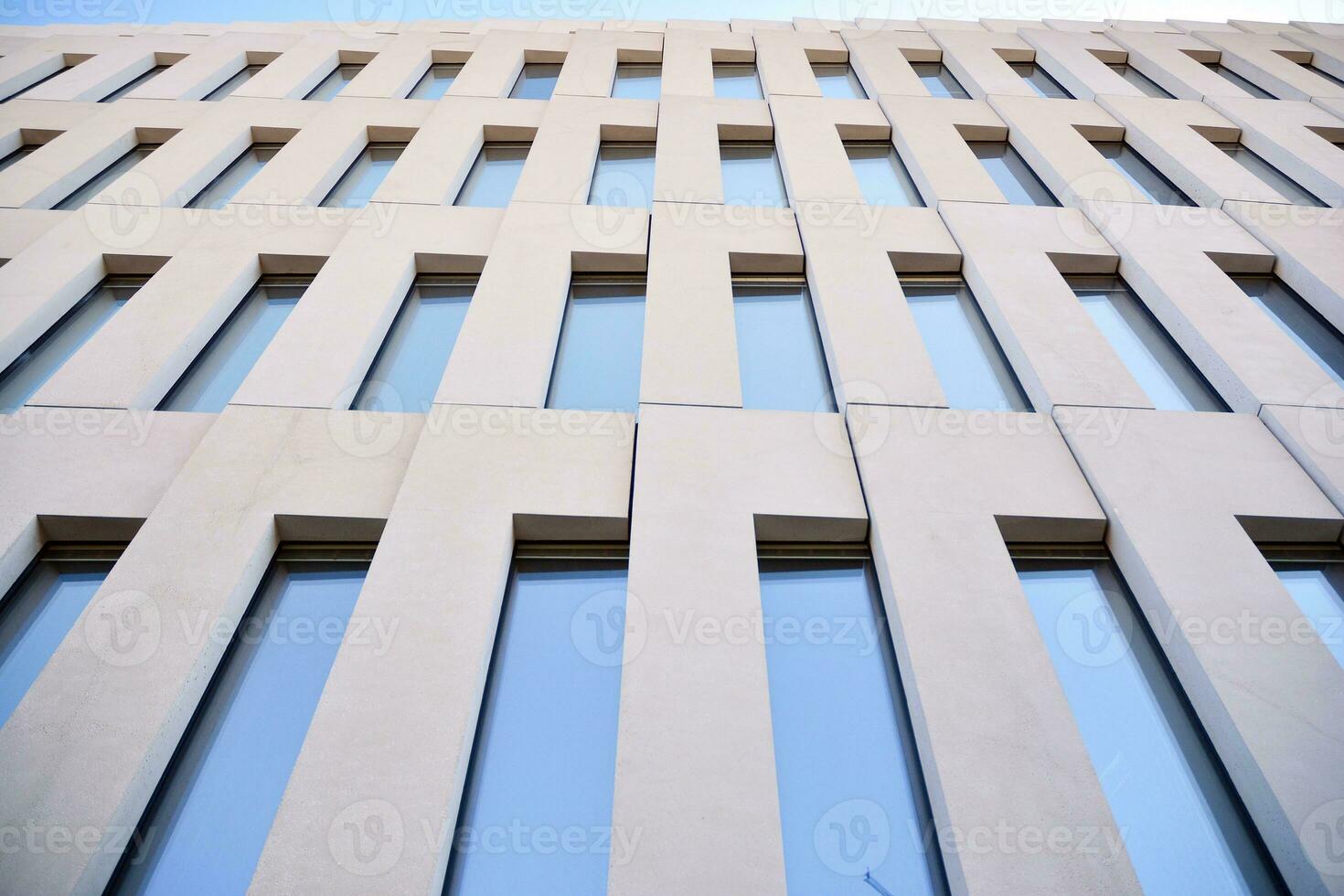 Modern office building detail. Perspective view of geometric angular concrete windows on the facade of a modernist brutalist style building. photo