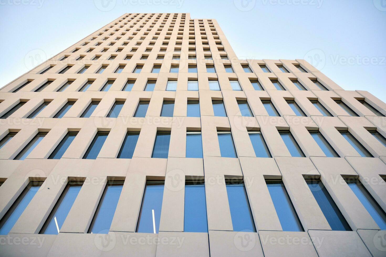 Modern office building detail. Perspective view of geometric angular concrete windows on the facade of a modernist brutalist style building. photo