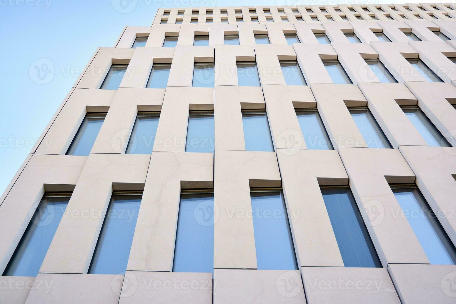 Modern office building detail. Perspective view of geometric angular concrete windows on the facade of a modernist brutalist style building. photo