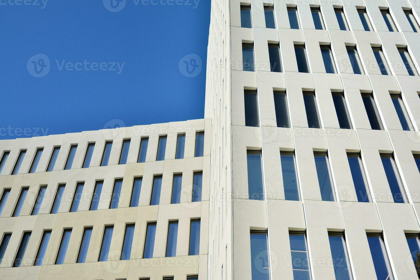Modern office building detail. Perspective view of geometric angular concrete windows on the facade of a modernist brutalist style building. photo