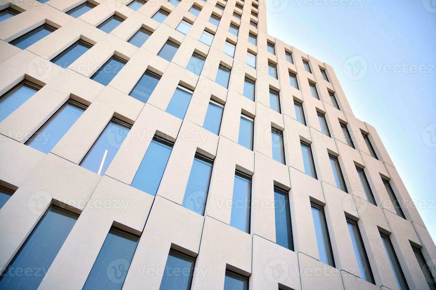 Modern office building detail. Perspective view of geometric angular concrete windows on the facade of a modernist brutalist style building. photo