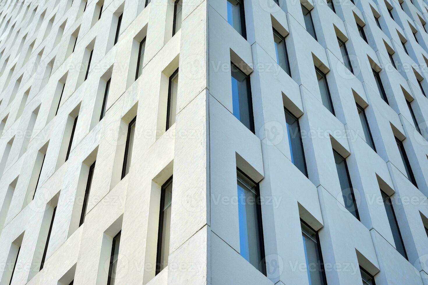 Modern office building detail. Perspective view of geometric angular concrete windows on the facade of a modernist brutalist style building. photo