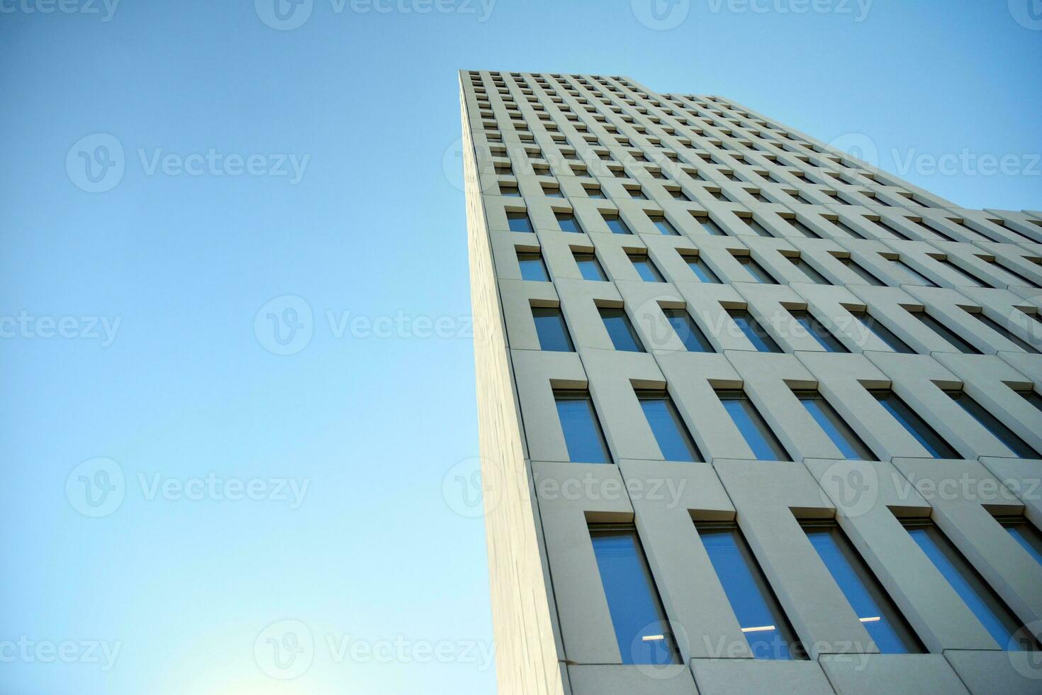 Modern office building detail. Perspective view of geometric angular concrete windows on the facade of a modernist brutalist style building. photo