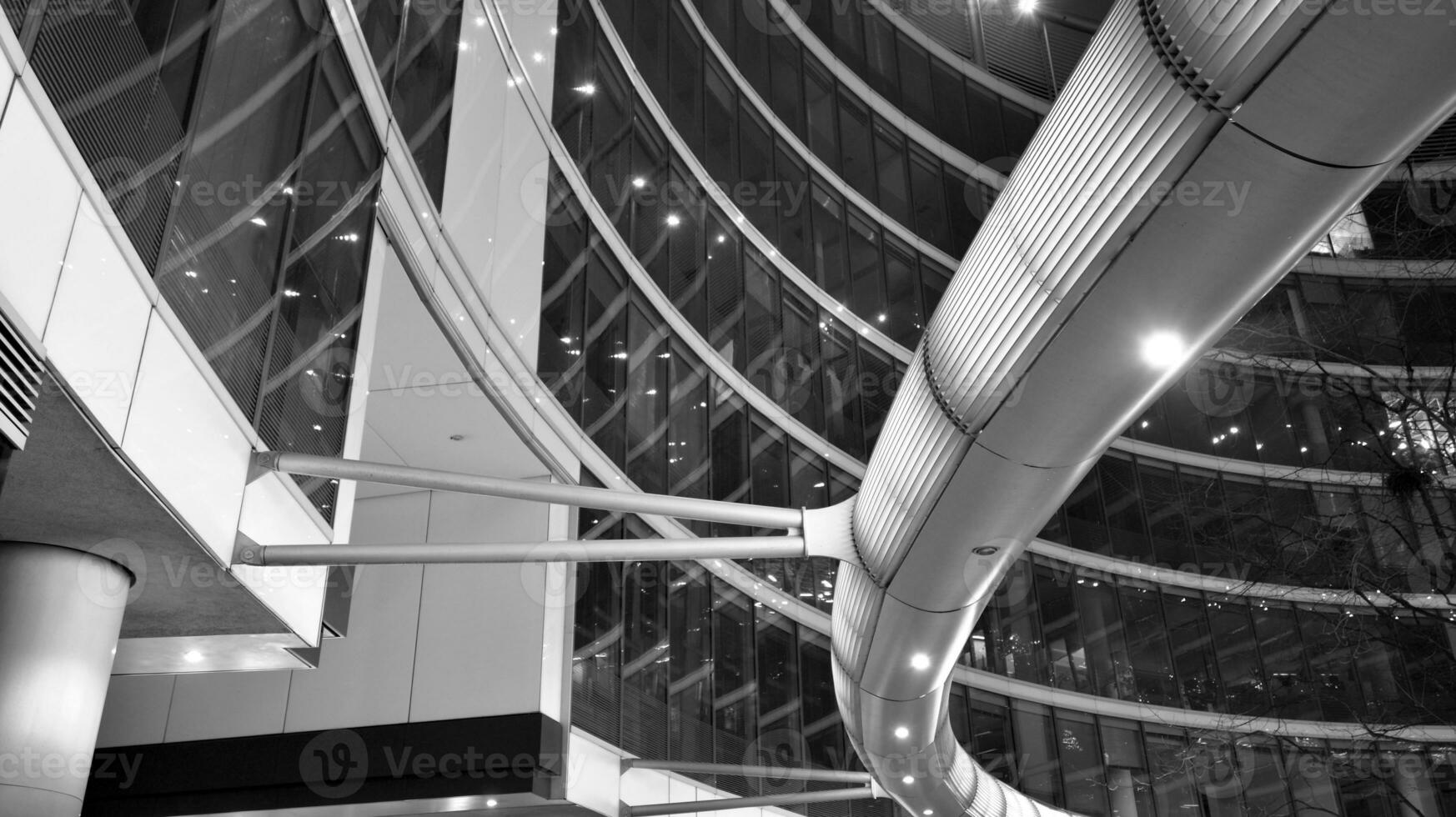 Amazing night cityscape. Office building at night, building facade with glass and lights. View with illuminated modern skyscraper. Scenic glowing windows of skyscrapers at evening. Black and white. photo