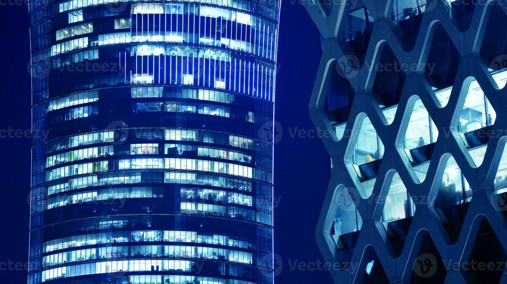 Pattern of office buildings windows illuminated at night. Glass architecture ,corporate building at night - business concept. Blue graphic filter. photo