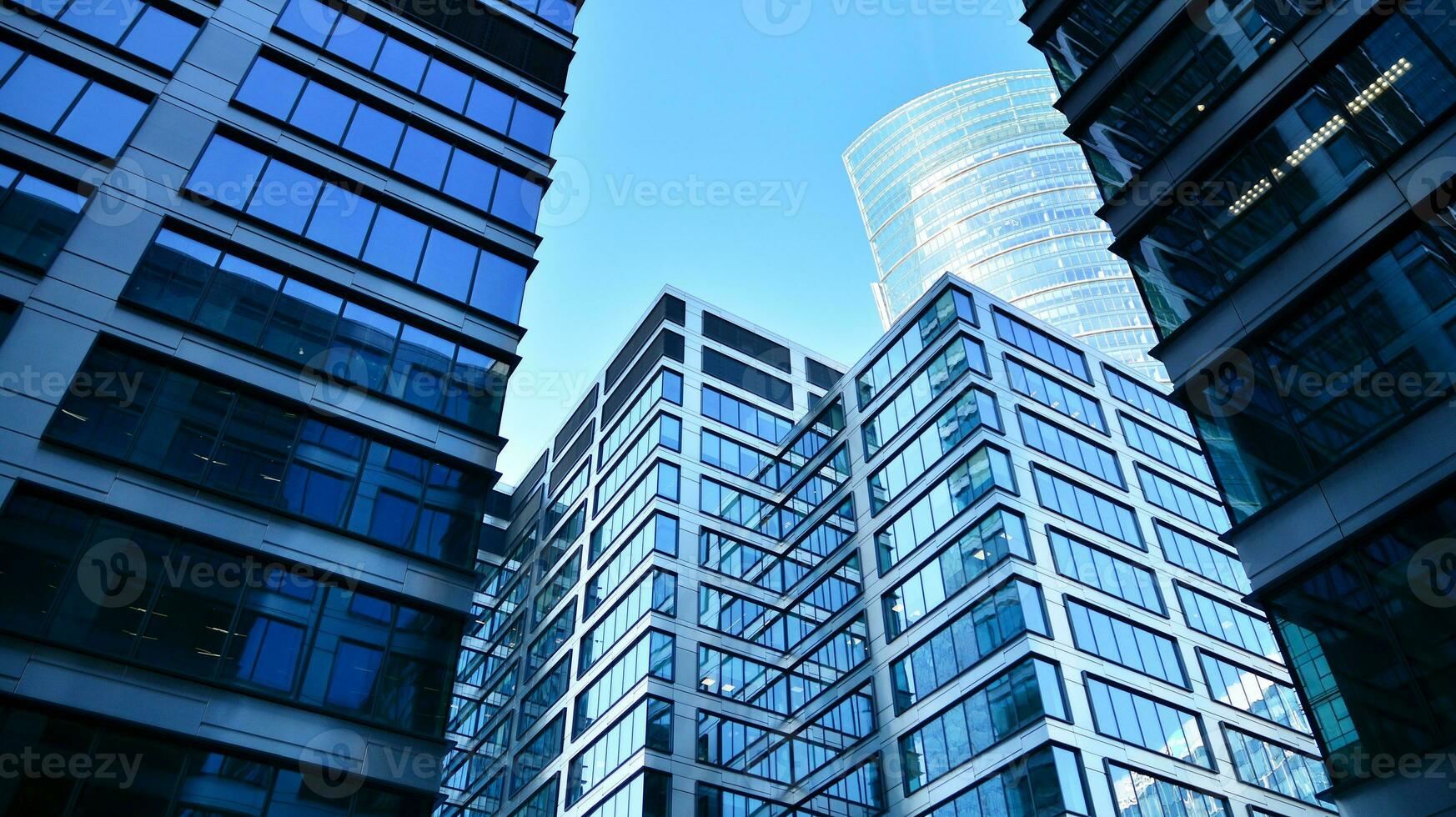 Bottom view of modern skyscrapers in business district against blue sky. Looking up at business buildings in downtown. photo