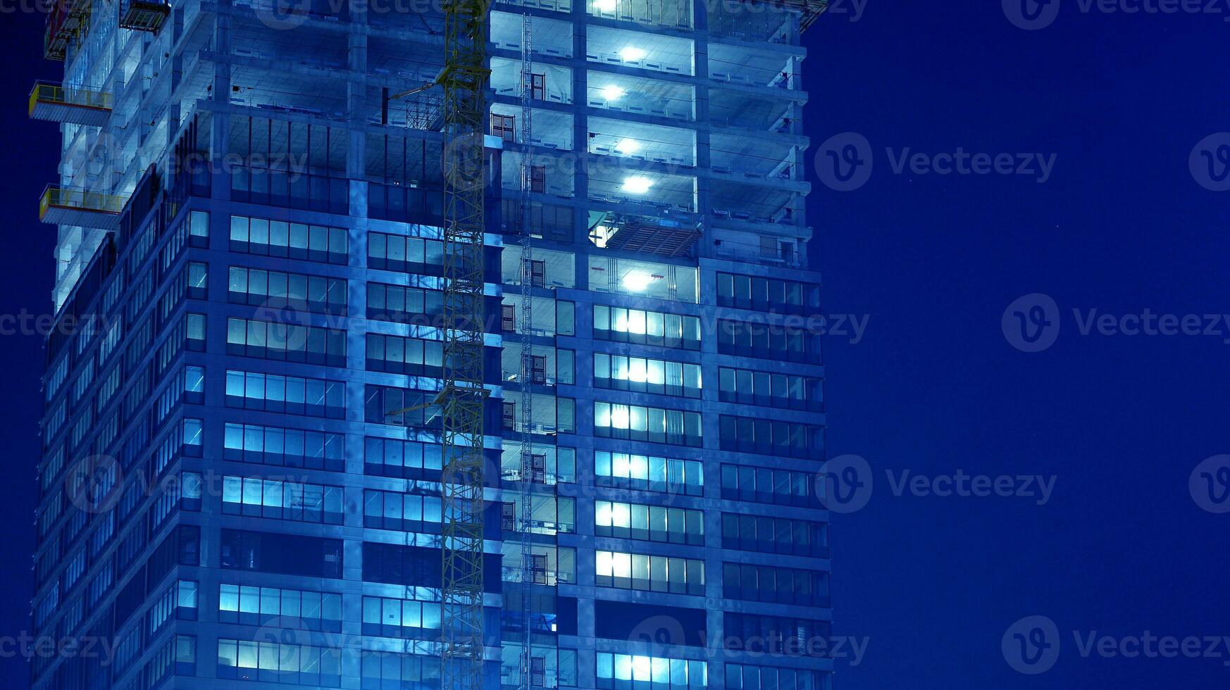 Pattern of office buildings windows illuminated at night. Glass architecture ,corporate building at night - business concept. Blue graphic filter. photo