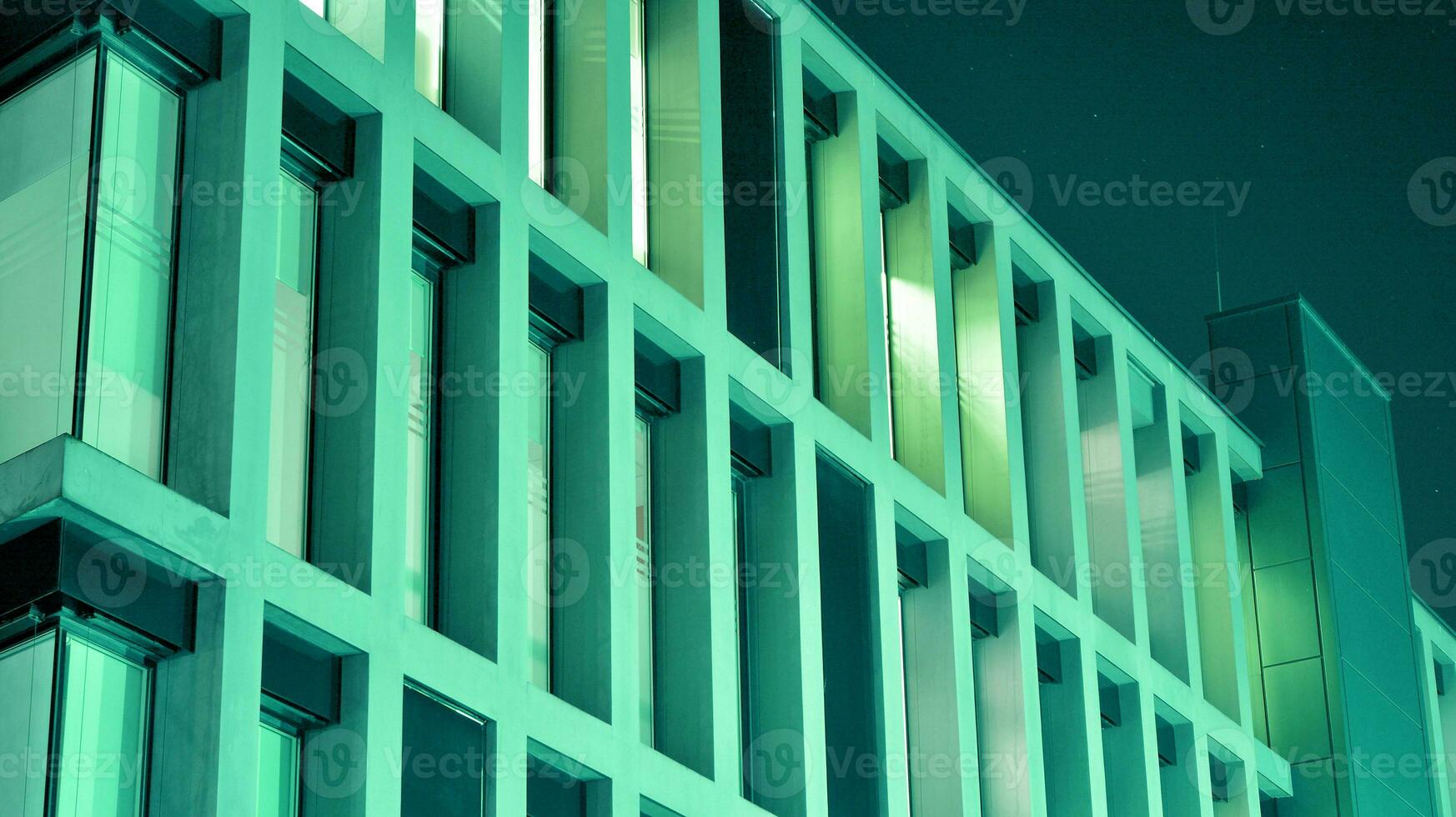 Night architecture - building with glass facade. Modern building in  business district. Concept of economics, financial. Photo of commercial office building exterior. Abstract image of office building