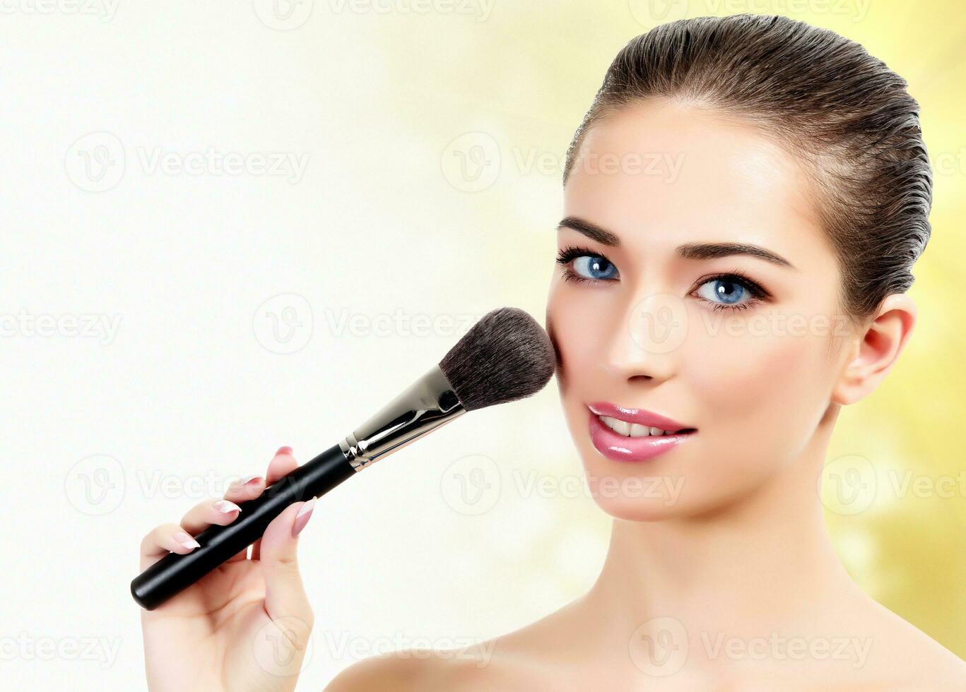 woman with cosmetic brushes against an abstract blurred background photo