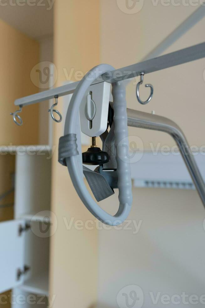 Gallow at the hospital bed in a hospital. Above hospital bed is hanging adaptive triangular metal frame. photo