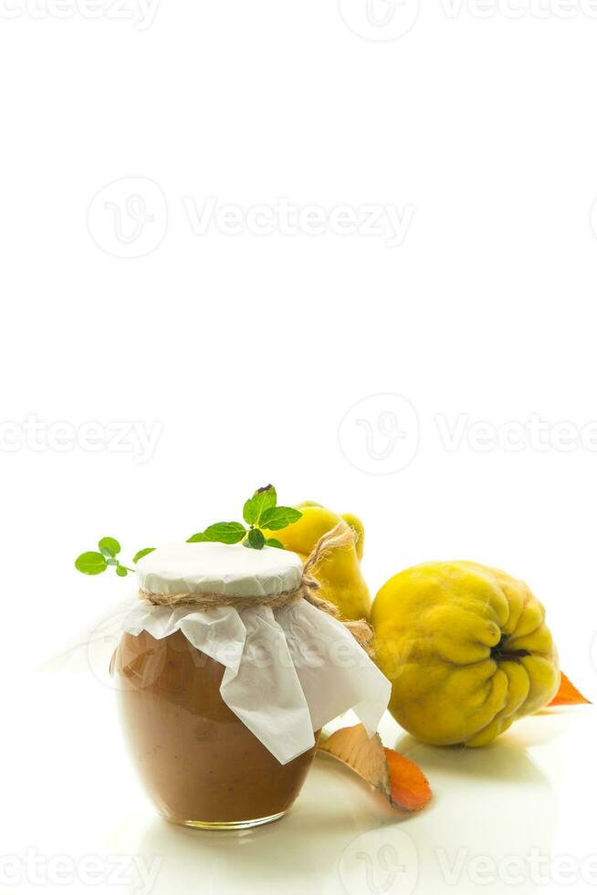 Ripe quince fruit with jam in a glass jar isolated on a white background. photo