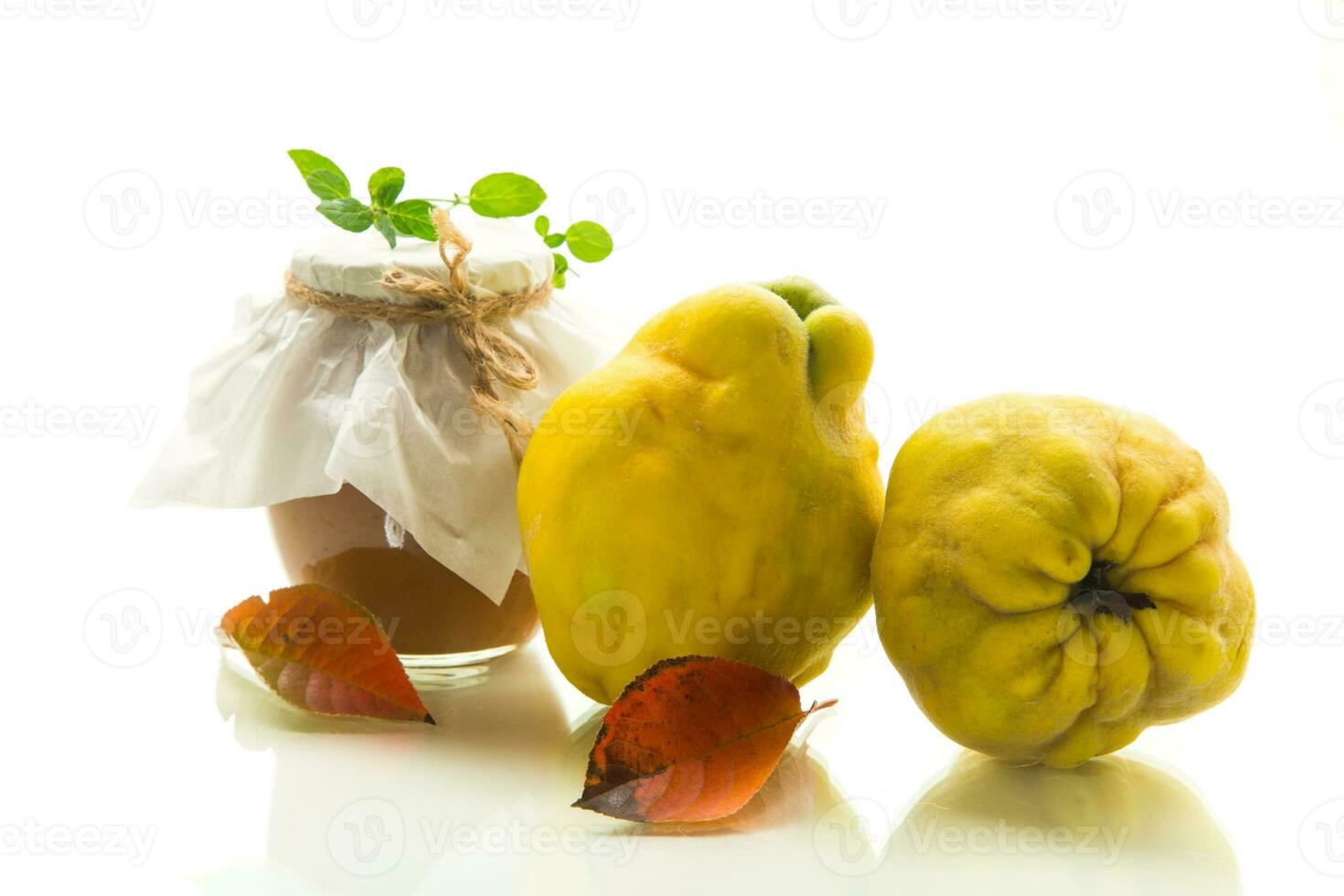 Ripe quince fruit with jam in a glass jar isolated on a white background. photo