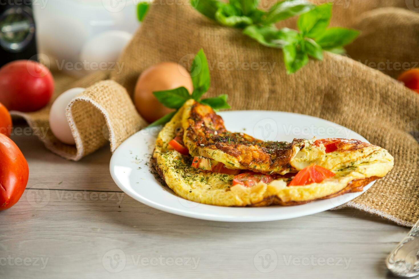 Stuffed omelette with tomatoes on a light wooden background. photo