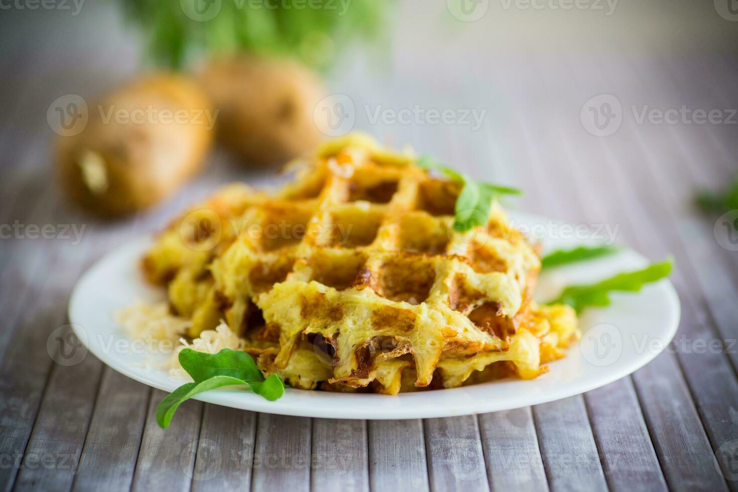 fried potato waffles with cheese in a plate on wooden table. photo