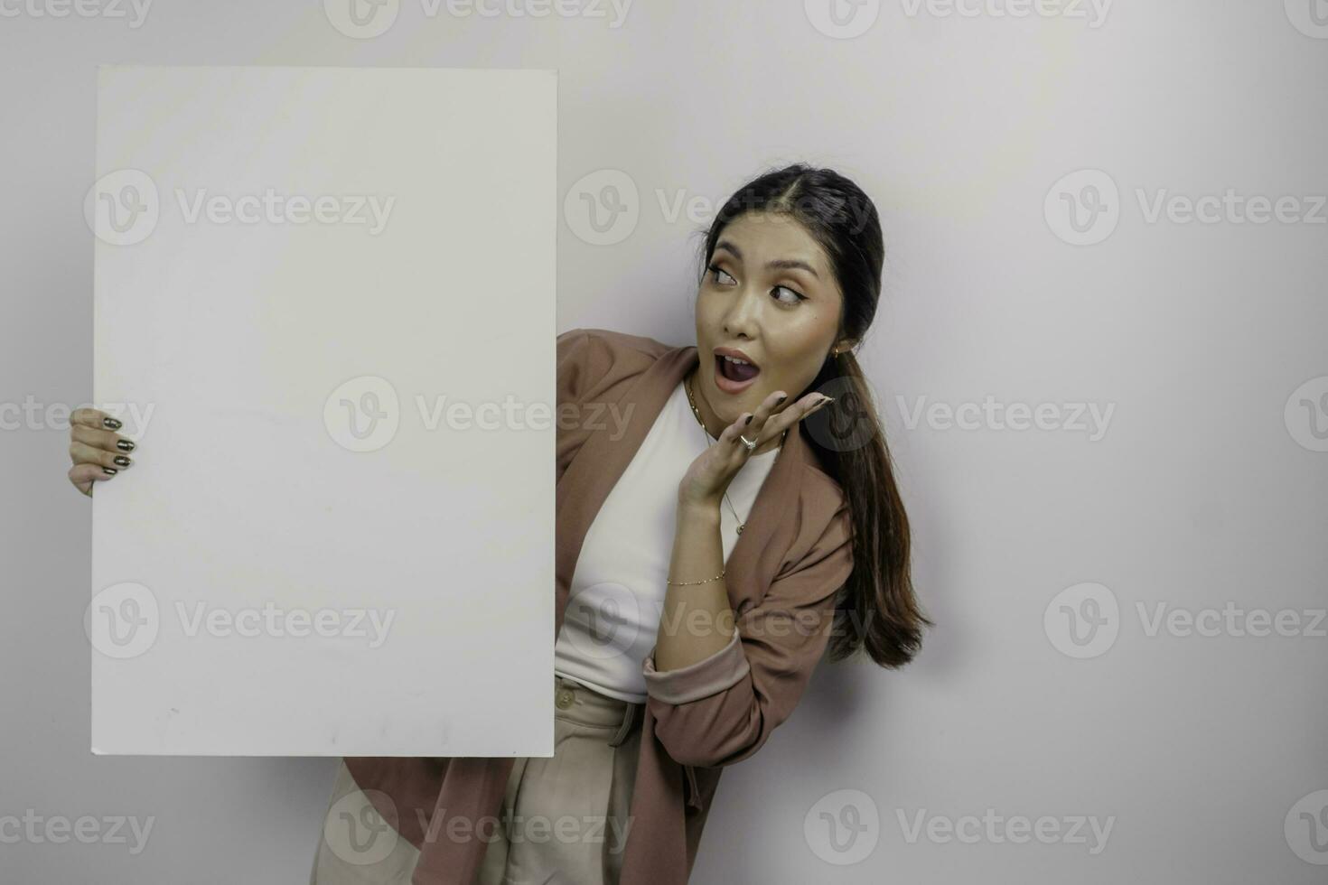 Shocked young Asian woman employee holding empty blank board, isolated by white background photo