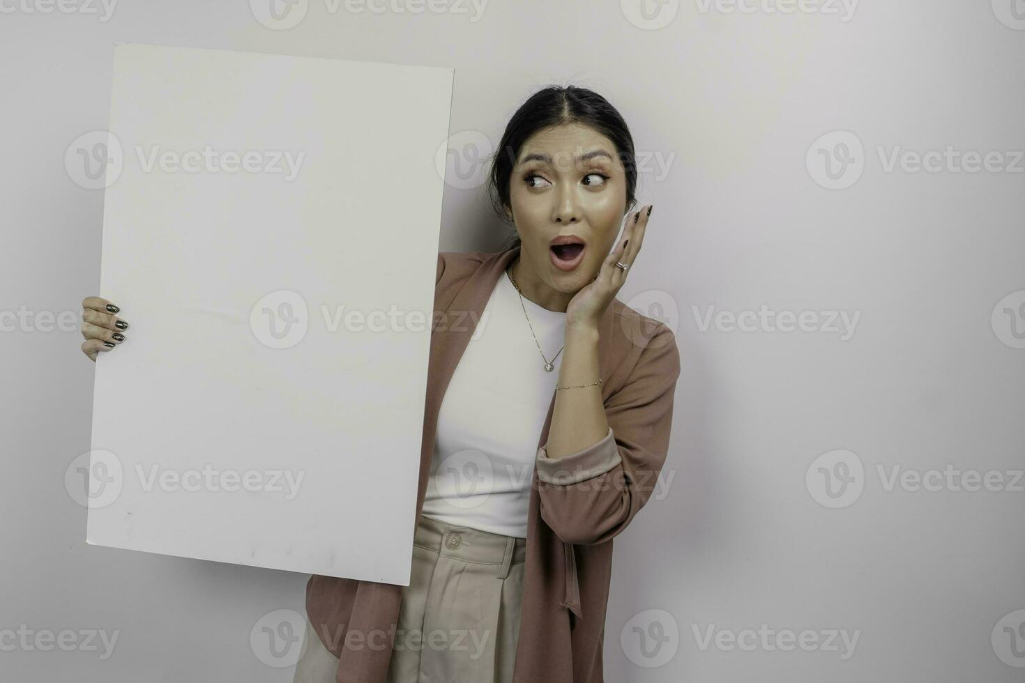 Shocked young Asian woman employee holding empty blank board, isolated by white background photo