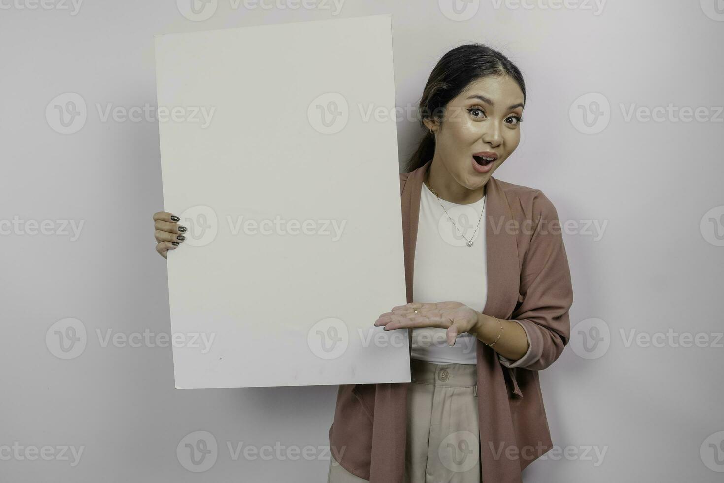 conmocionado joven asiático mujer empleado participación vacío blanco junta, aislado por blanco antecedentes foto
