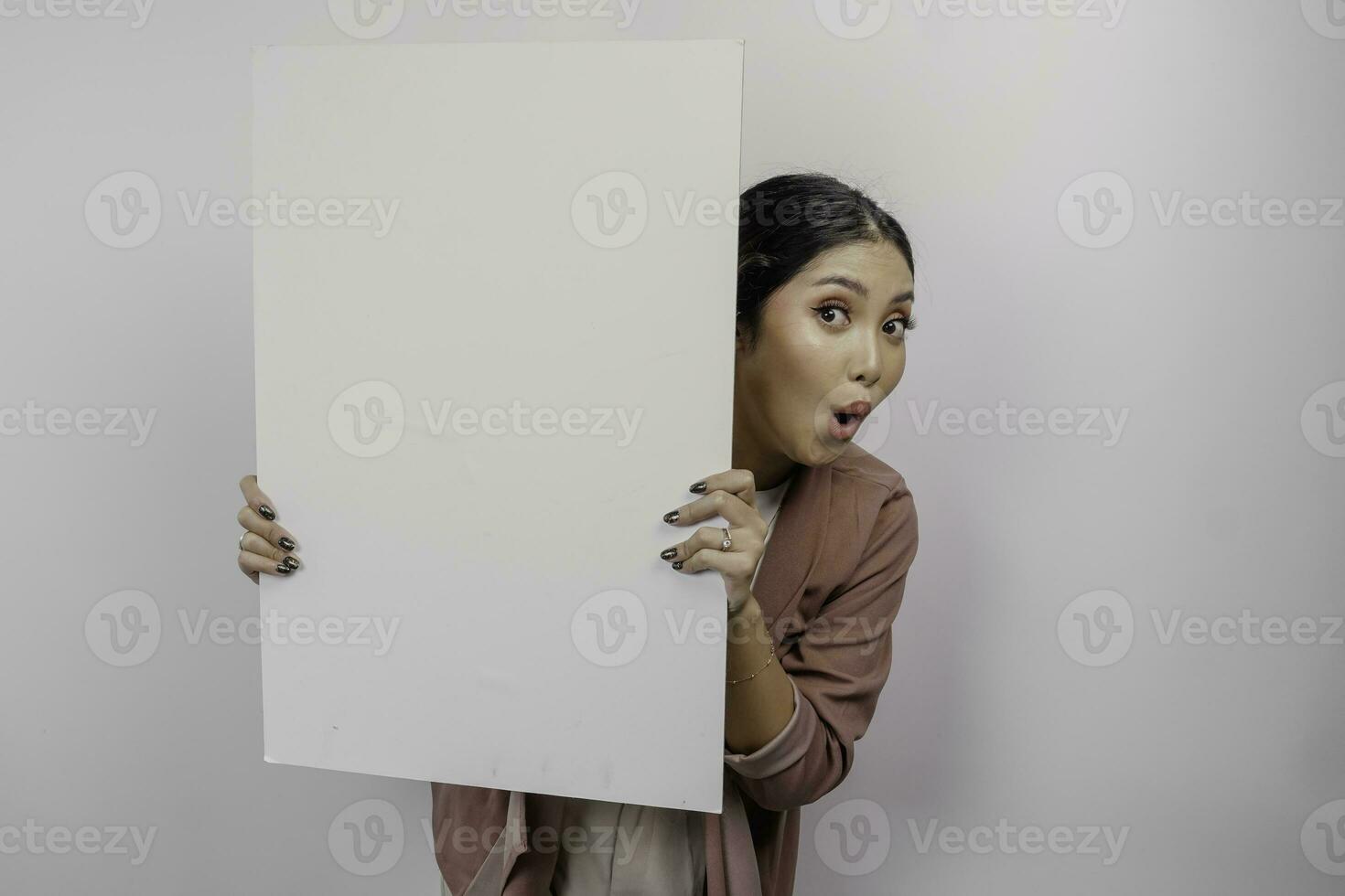 conmocionado joven asiático mujer empleado participación vacío blanco junta, aislado por blanco antecedentes foto